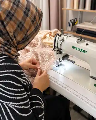 Tailor working with fabric at a sewing machine, face not visible