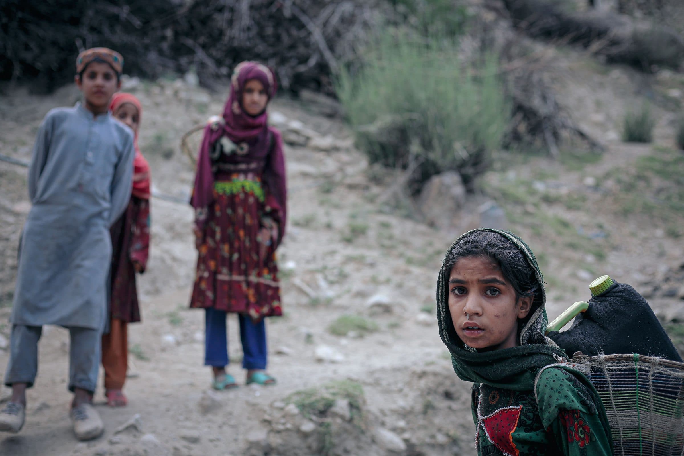 Children in a rural Afghan village walking along a mountain footpath